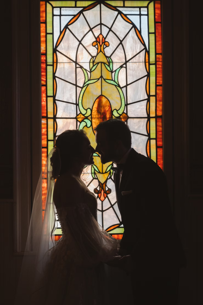Bride and groom for wedding day portrait in front of stained glass window at David's Country Inn in Hackettstown, New Jersey.  Photographed by South Jersey, Philadelphia based wedding photographer Madison Neumann Photography.