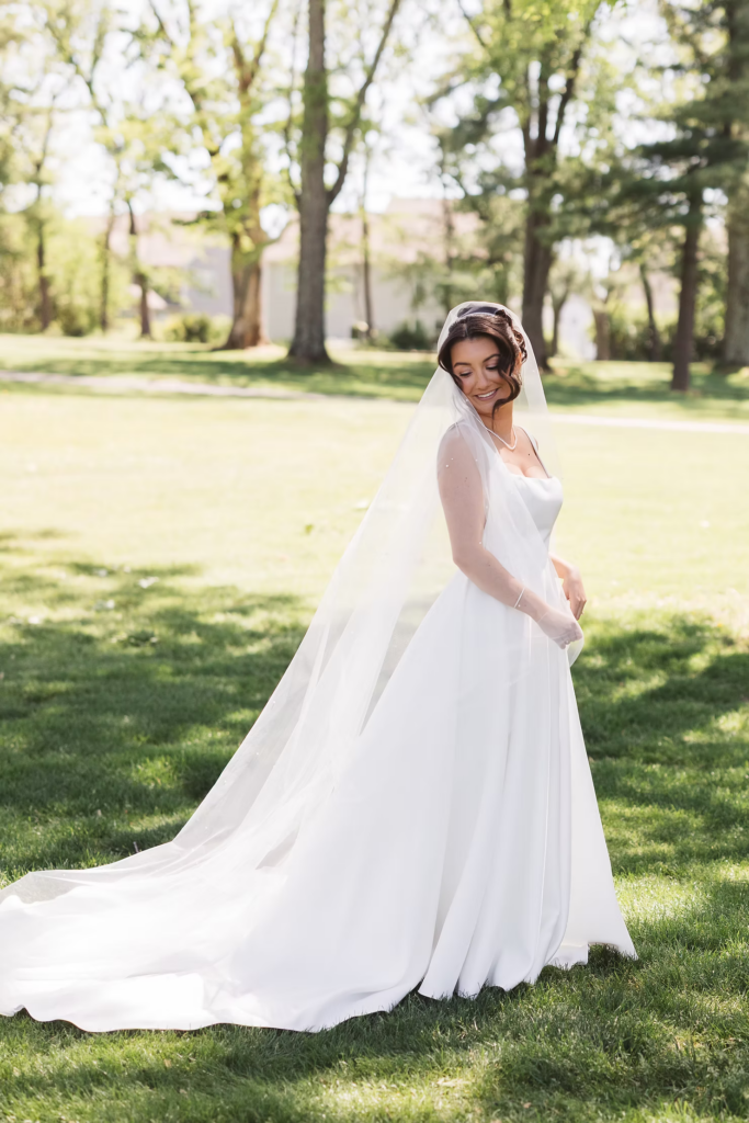 Bride stands outside wearing wedding gown and veil, smiling. Wedding day at Downingtown Country Club in Downingtown, PA. Photographed by South Jersey, Philadelphia based wedding photographer Madison Neumann Photography.
