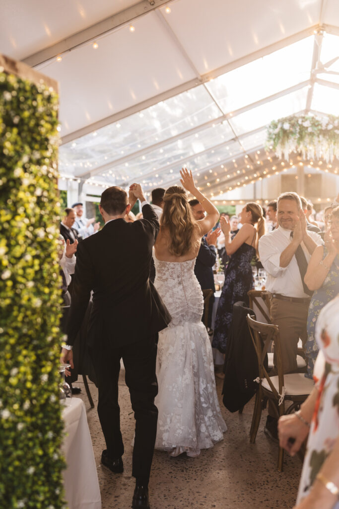 Guests cheer for bride and groom as they enter wedding reception. Wedding day at the American Swedish Historical Museum in Philadelphia, PA. Photographed by South Jersey/Philly based wedding photographer Madison Neumann Photography.