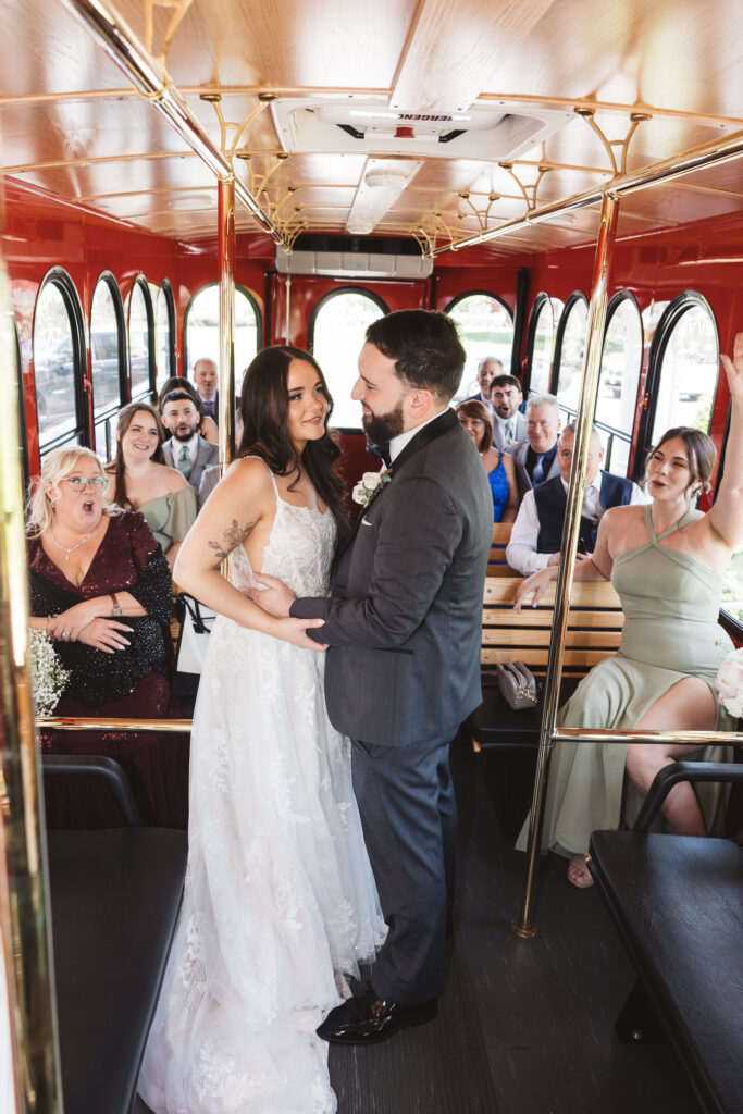 Wedding guests cheer for bride and groom on red trolley ride. Wedding day at Blue Heron Pines Golf Club in Egg Harbor, NJ. Photographed by South Jersey/Philly based wedding photographer Madison Neumann Photography.