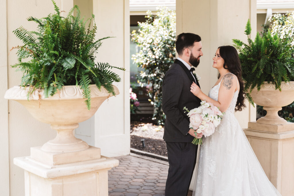 Bride and groom smile together outside in front of plants. Wedding day at Blue Heron Pines Golf Club in Egg Harbor, NJ. Photographed by South Jersey/Philly based wedding photographer Madison Neumann Photography.