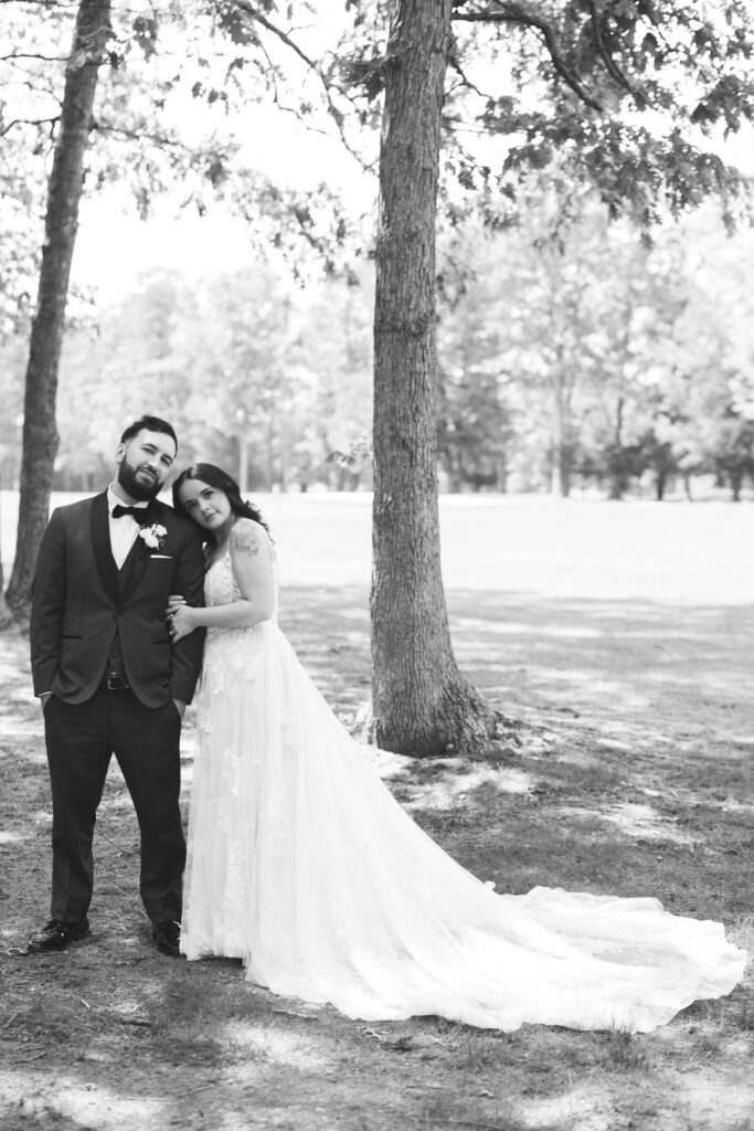 Black and white portrait of bride and groom in front of trees. Wedding day at Blue Heron Pines Golf Club in Egg Harbor, NJ. Photographed by South Jersey/Philly based wedding photographer Madison Neumann Photography.