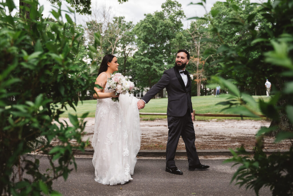 Groom holds brides hand as they walk. Wedding day at Blue Heron Pines Golf Club in Egg Harbor, NJ. Photographed by South Jersey/Philly based wedding photographer Madison Neumann Photography.