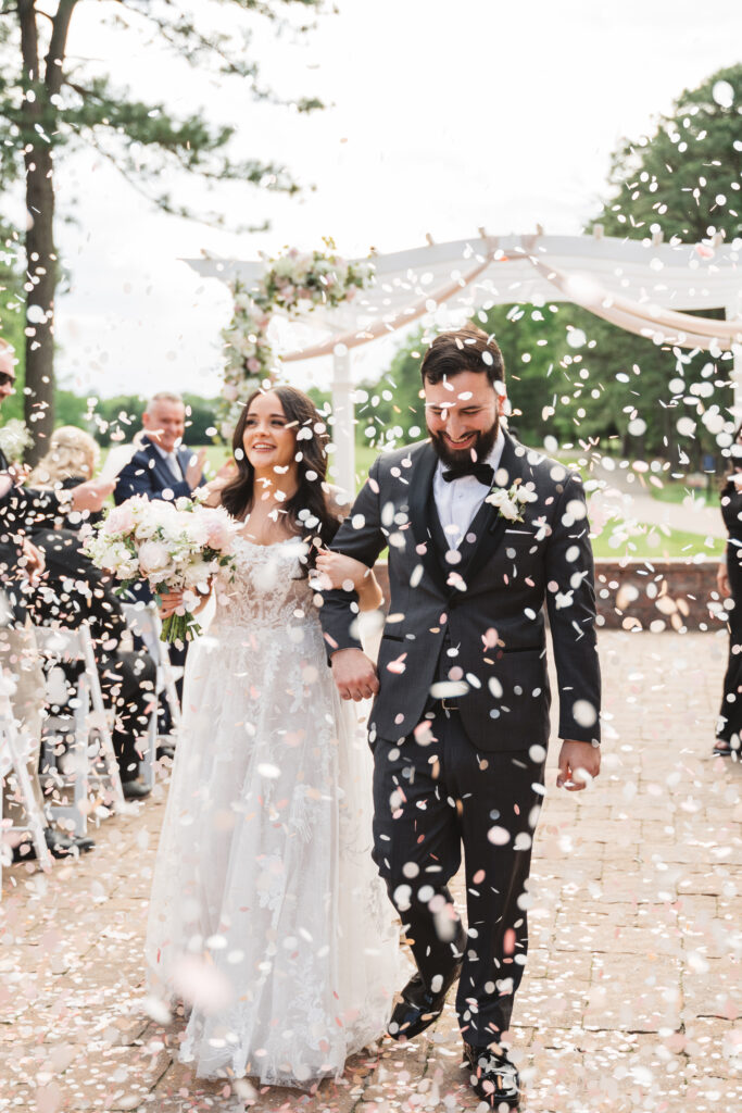 Guests shower bride and groom with pedals as they exit their ceremony. Wedding day at Blue Heron Pines Golf Club in Egg Harbor, NJ. Photographed by South Jersey/Philly based wedding photographer Madison Neumann Photography.