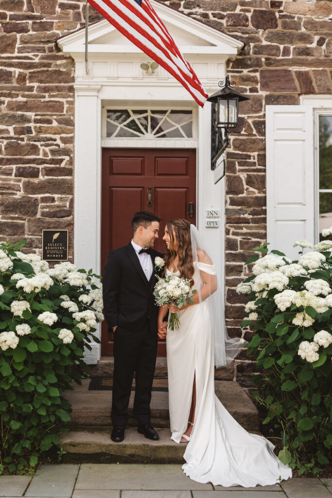 Bride and groom holding hands and looking at each other on the steps of the Woolverton Inn, photographed by New Jersey and Philadelphia based travel wedding photographer Madison Neumann Photography.