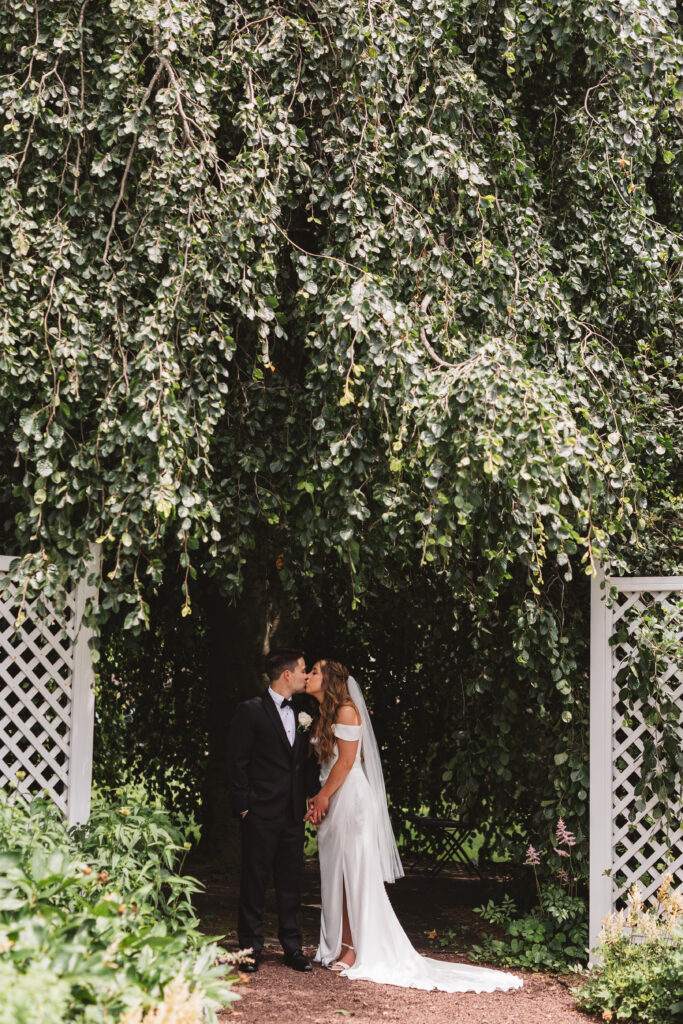 Bride and groom under a tree sharing a kiss before the ceremony, photographed by New Jersey and Philadelphia based travel wedding photographer Madison Neumann Photography.