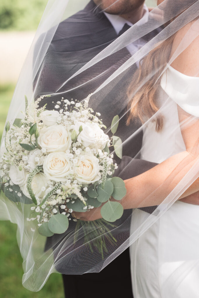 Detail shot of bouquet beneath the brides veil as the couple embrace one another, photographed by New Jersey and Philadelphia based travel wedding photographer Madison Neumann Photography.