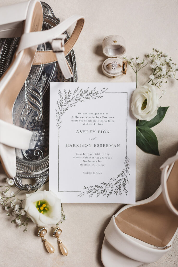 Flat lay of invitation with flowers, rings, and bride's heels, photographed by New Jersey and Philadelphia based travel wedding photographer Madison Neumann Photography.