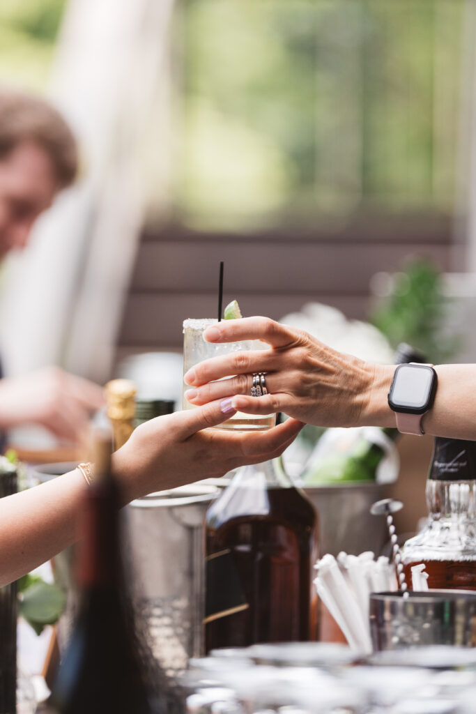 Bartender handing one of the signature drinks to a guest during cocktail hour, photographed by New Jersey and Philadelphia based travel wedding photographer Madison Neumann Photography.