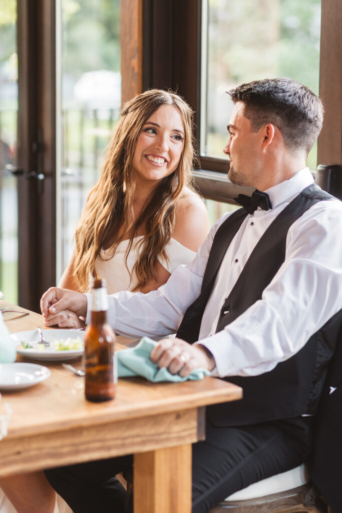 Bride and groom smiling at each other at their table during speeches, photographed by New Jersey and Philadelphia based travel wedding photographer Madison Neumann Photography.