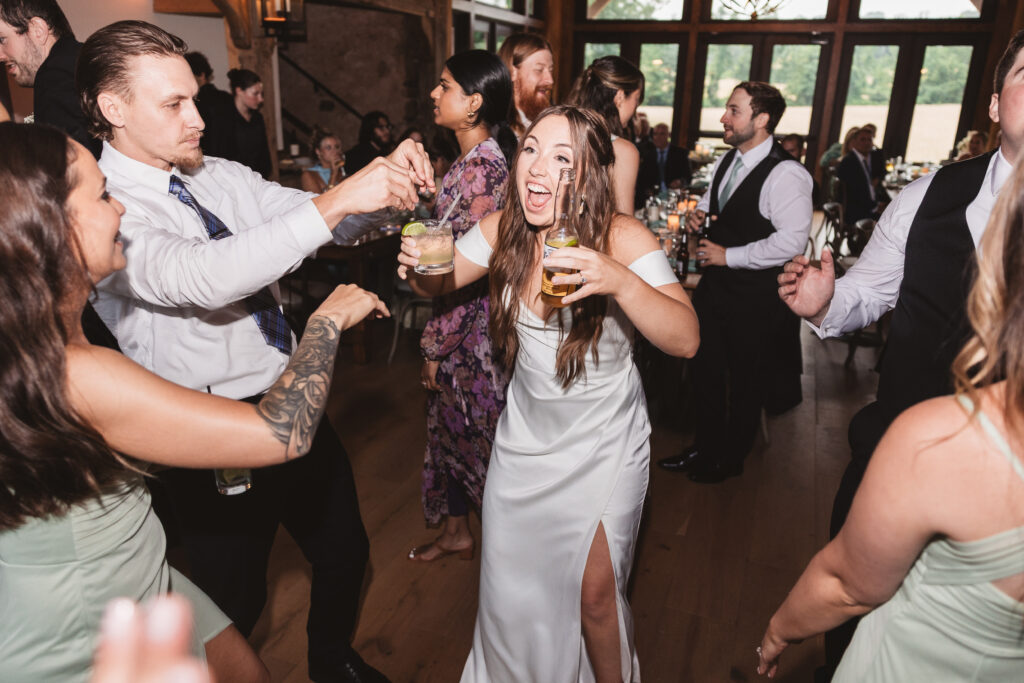Bride holding two drinks on the dance floor greeting friends and family, photographed by New Jersey and Philadelphia based travel wedding photographer Madison Neumann Photography.