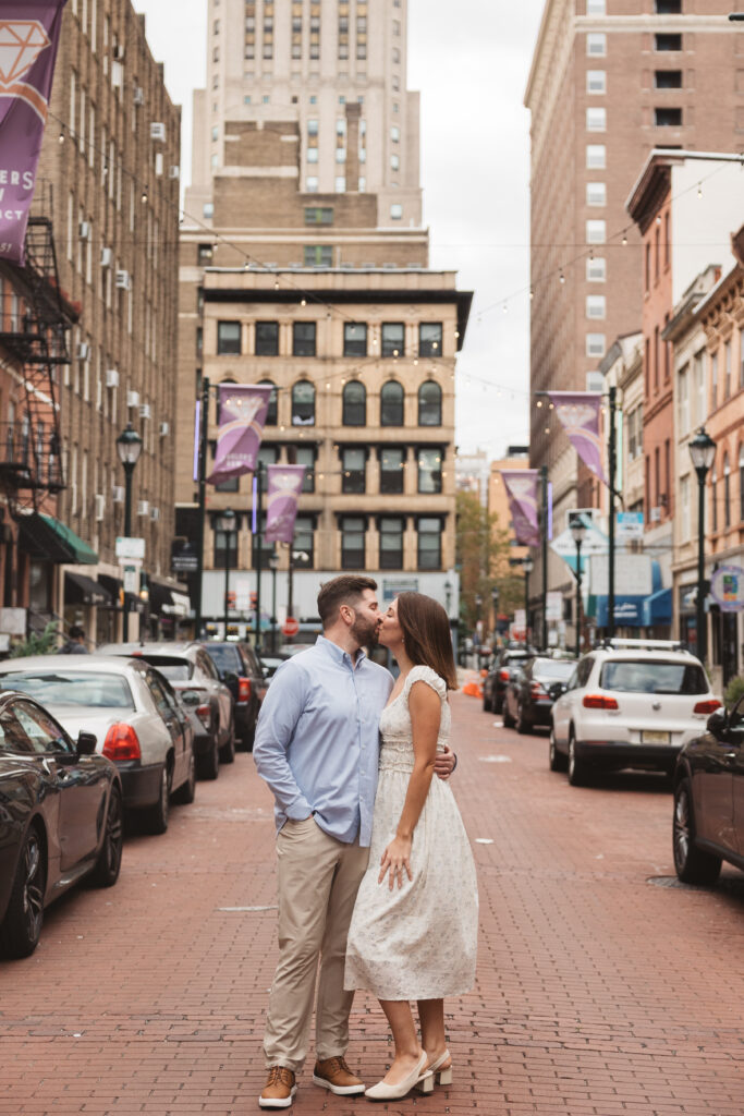 Couple shares a kiss on jewelers row in old city, Philadelphia, photographed by Philadelphia and New Jersey based travel wedding photographer, Madison Neumann Photography.