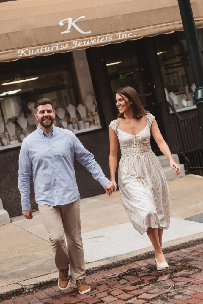 Young couple holds hands as they cross the street, photographed by Philadelphia and New Jersey based travel wedding photographer, Madison Neumann Photography.