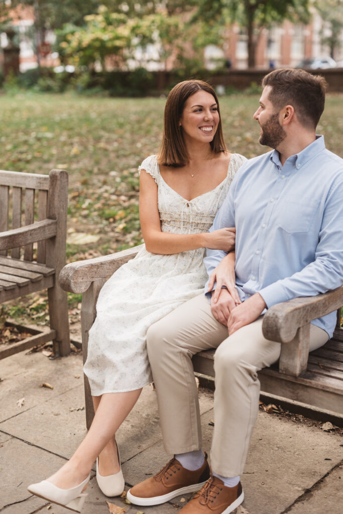Future bride and groom sit on a bench together in Washington Square park, photographed by Philadelphia and New Jersey based travel wedding photographer, Madison Neumann Photography.