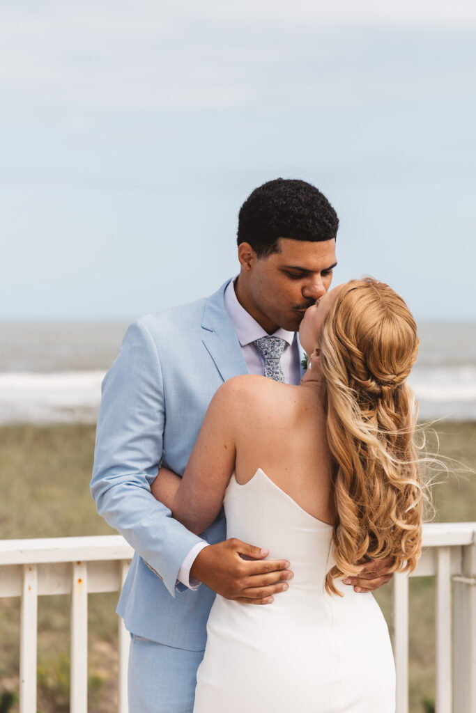 Bride and groom share a kiss outside on the balcony before saying private vows in Outer Banks, photographed by New Jersey and Philadelphia based travel wedding photographer, Madison Neumann Photography.