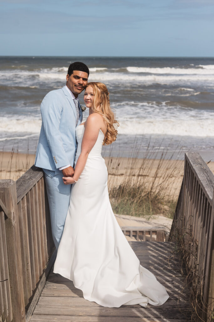 Bride and groom on dock with the ocean waves of the Outer Banks in background, photographed by New Jersey and Philadelphia based travel wedding photographer, Madison Neumann Photography.