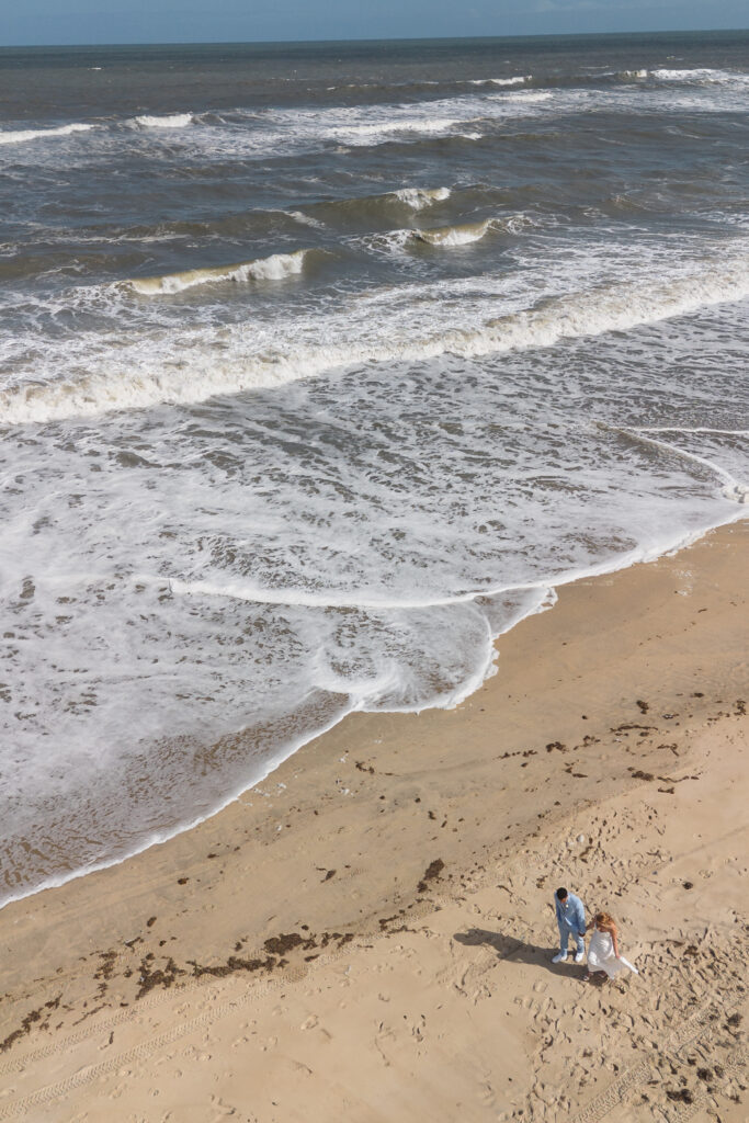 Overhead establishing drone shot of bride and groom on Outer Banks beach, photographed by New Jersey and Philadelphia based travel wedding photographer, Madison Neumann Photography.