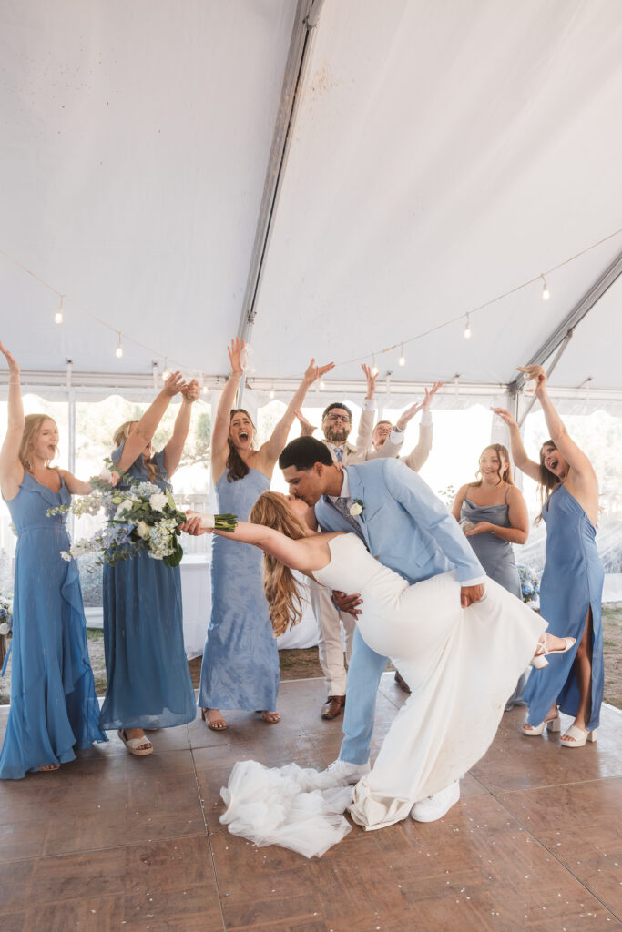 Groom dips his bride for a romantic kiss surrounded by the bridesmaids, photographed by New Jersey and Philadelphia based travel wedding photographer, Madison Neumann Photography.