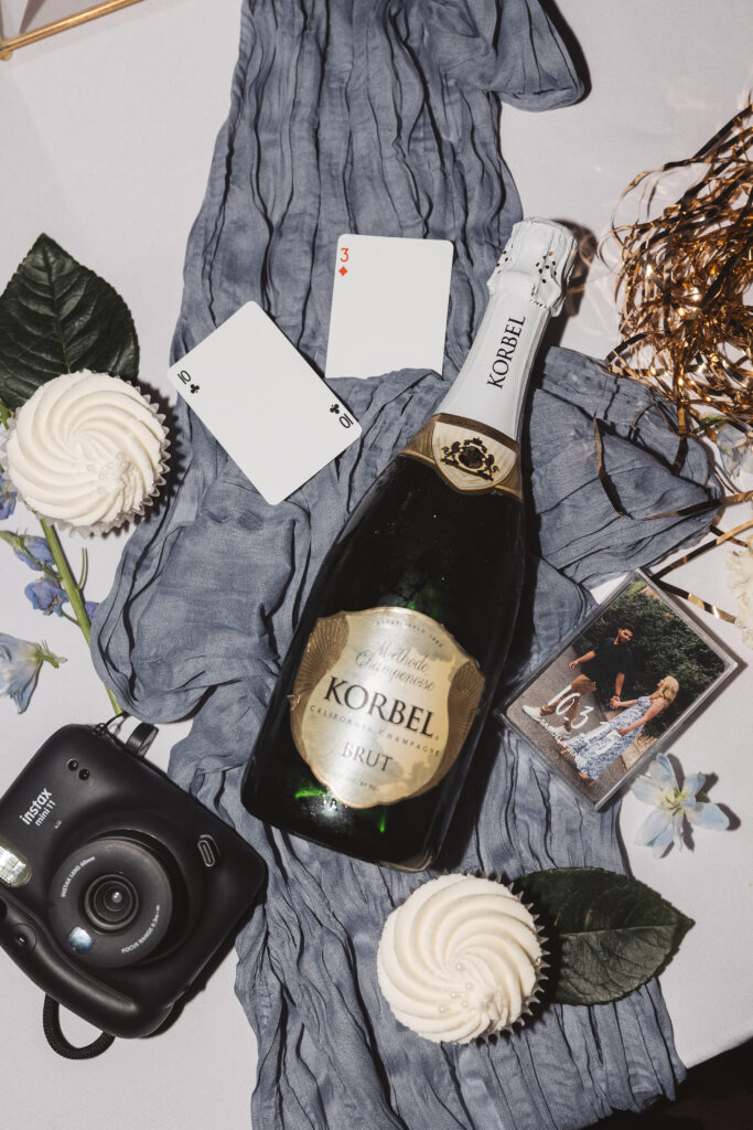 Flat lay of champagne, cupcakes, flowers, and other party items, photographed by New Jersey and Philadelphia based travel wedding photographer, Madison Neumann Photography.