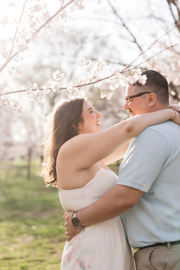 Bride has her hands resting around her fiancé's neck as they smile at each other in fairmont park, photographed by Philadelphia and New Jersey based travel wedding photographer, Madison Neumann Photography.