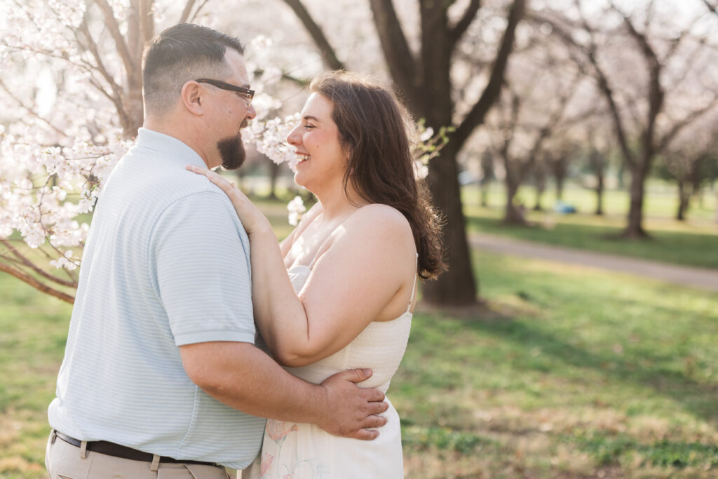 Couple holds each other smiling in from of a blossom tree, photographed by Philadelphia and New Jersey based travel wedding photographer, Madison Neumann Photography.