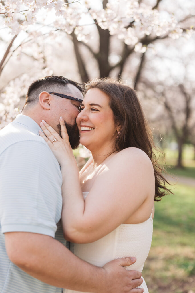Groom kisses bride on her cheek as she smiles and holds his face with her left hands, showing off her beautiful ring, photographed by Philadelphia and New Jersey based travel wedding photographer, Madison Neumann Photography.
