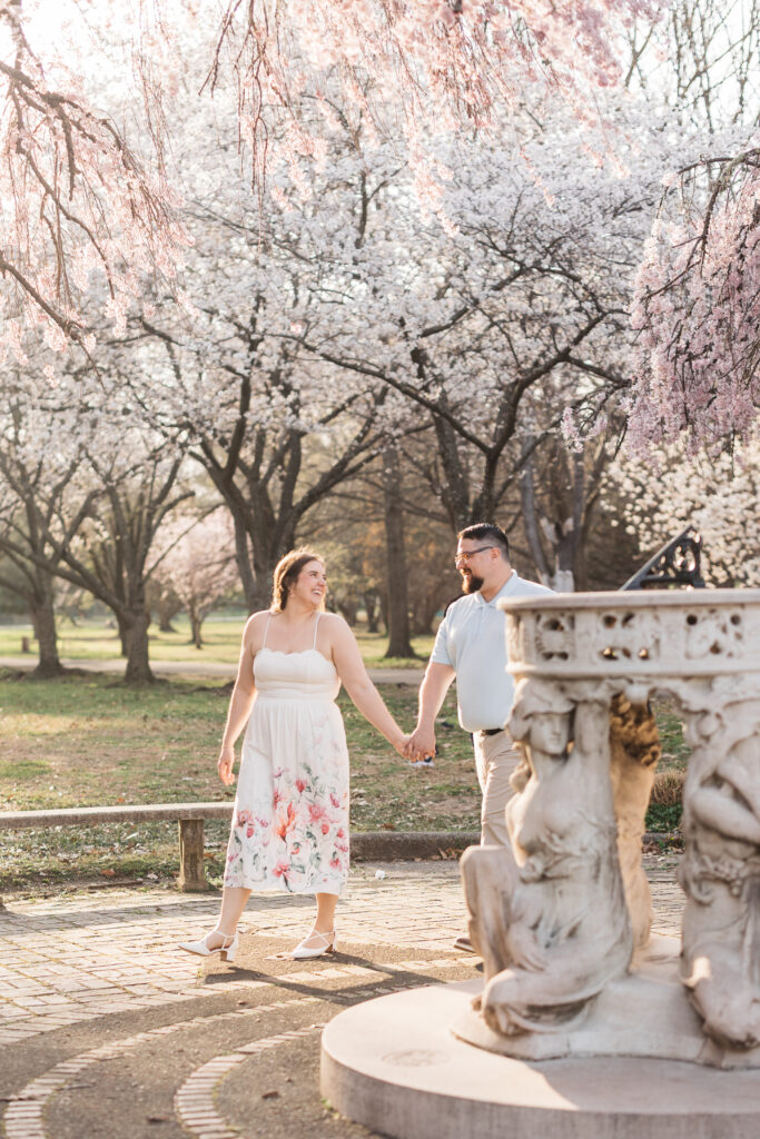 Bride and groom hand in hand as she leads them around a fountain as they laugh and look at each other, photographed by Philadelphia and New Jersey based travel wedding photographer, Madison Neumann Photography.