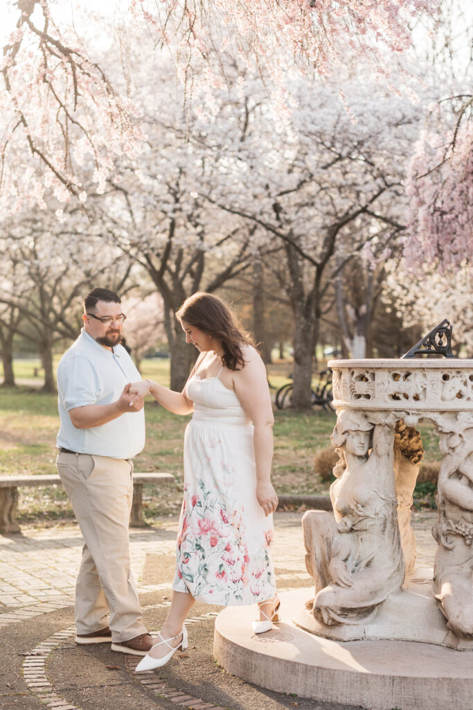 Groom offers a hand to his bride and helps her down from a step that surrounds the fountain, photographed by Philadelphia and New Jersey based travel wedding photographer, Madison Neumann Photography.
