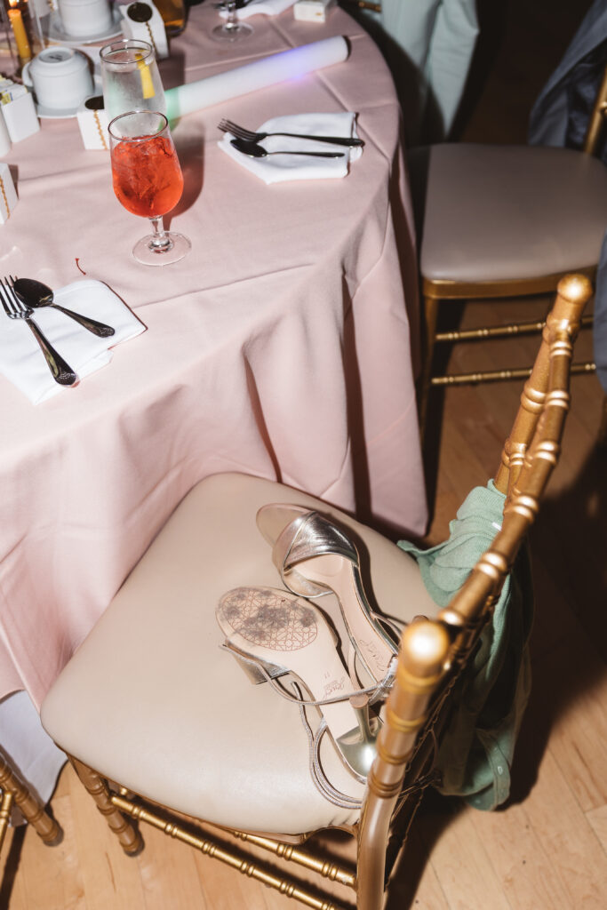 End of the night detail shot of the cocktails on the table and heels on the chair, photographed by Philadelphia and New Jersey based travel wedding photographer, Madison Neumann Photography.