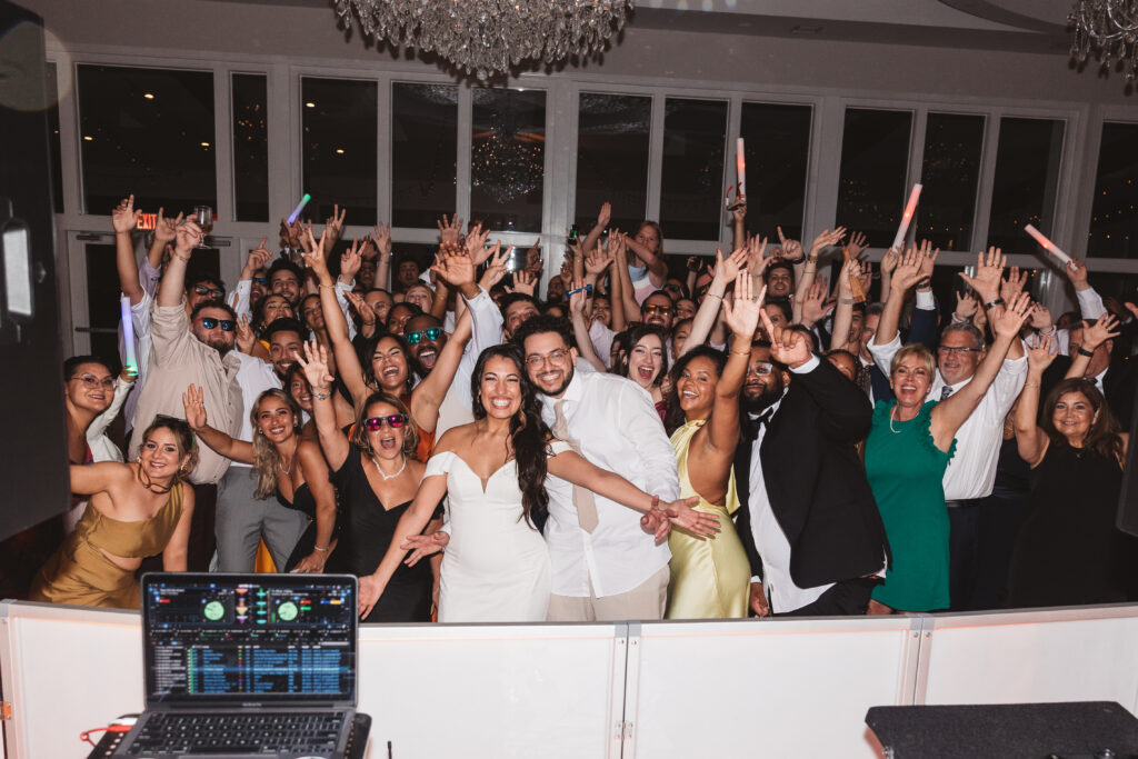 Photo of all guests and dj with the newly-weds on the dance floor waving at the camera, photographed by Philadelphia and New Jersey based travel wedding photographer, Madison Neumann Photography.