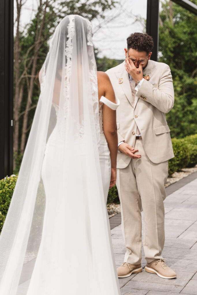 First look, grooms reaction taken from behind the beautiful bride. Groom is wiping his eyes, photographed by Philadelphia and New Jersey based travel wedding photographer, Madison Neumann Photography.