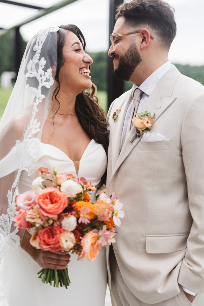 Portrait of the bride and groom outside of Skyview Golf Club smiling at one another, photographed by Philadelphia and New Jersey based travel wedding photographer, Madison Neumann Photography.