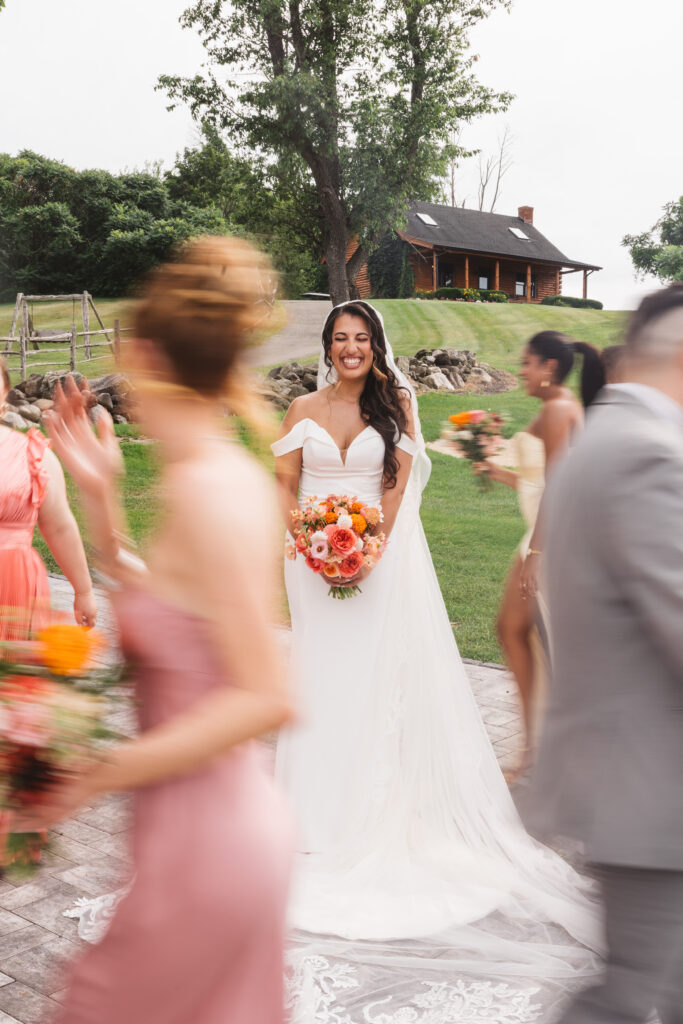 Bride smiling while the wedding party runs around her in a blur, photographed by Philadelphia and New Jersey based travel wedding photographer, Madison Neumann Photography.