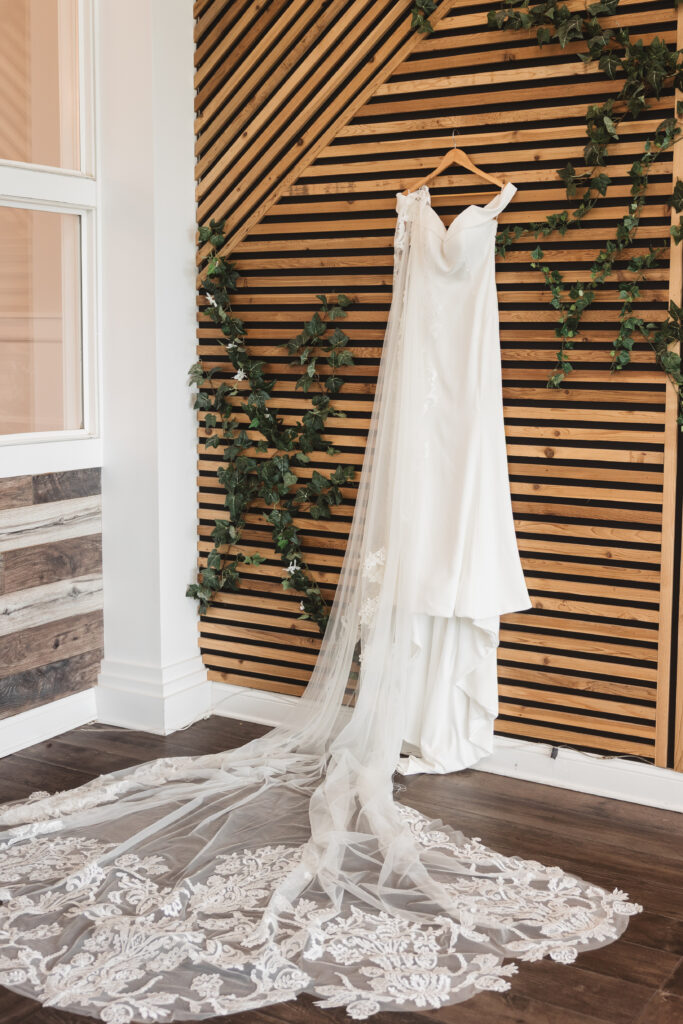 Brides dress hung on a decorative wood wall with vines, photographed by Philadelphia and New Jersey based travel wedding photographer, Madison Neumann Photography.
