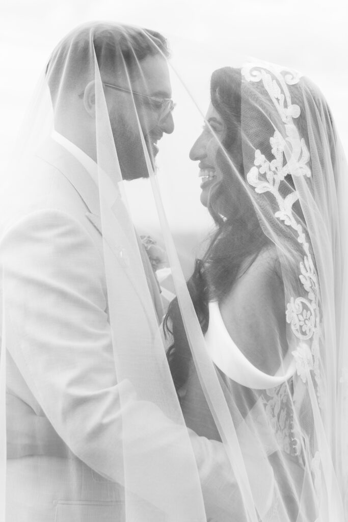 Black and white close up of bride and groom smiling at each other under the veil, photographed by Philadelphia and New Jersey based travel wedding photographer, Madison Neumann Photography.