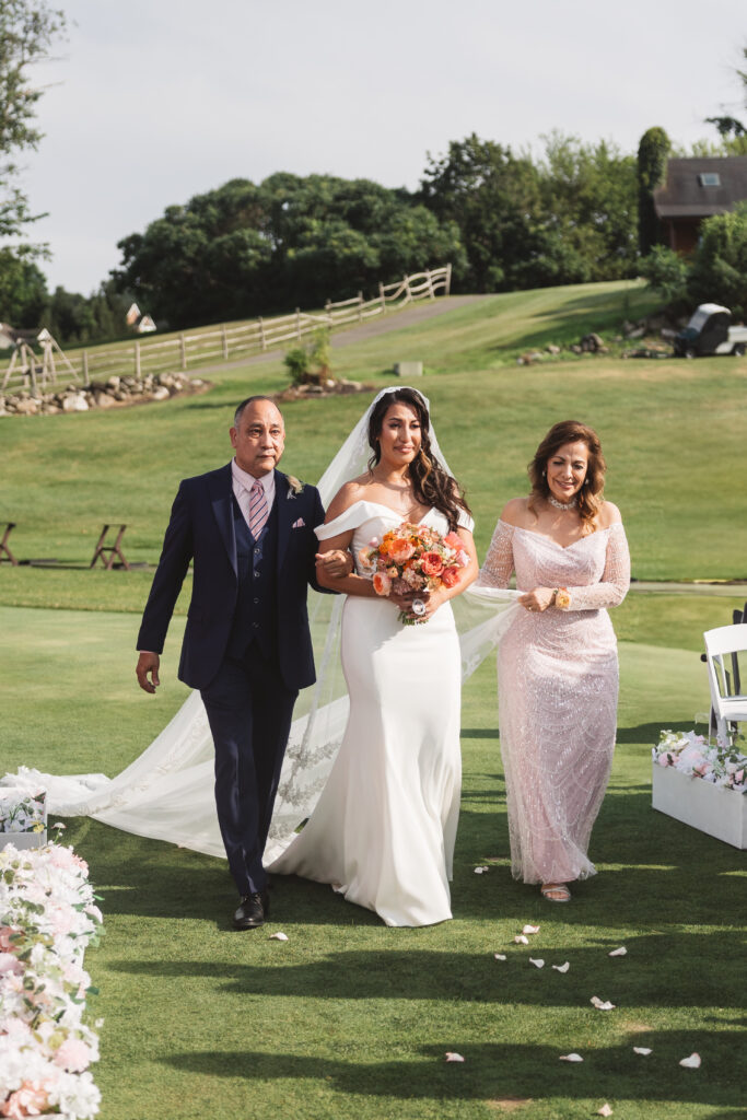 Bride escorted down the aisle by her father and mother as her mother holds her veil, photographed by Philadelphia and New Jersey based travel wedding photographer, Madison Neumann Photography.