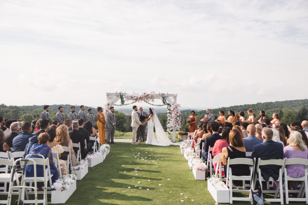 Horizontal shot of bride and groom at the altar on the freshly cut grass surrounded by friends and family, photographed by Philadelphia and New Jersey based travel wedding photographer, Madison Neumann Photography.