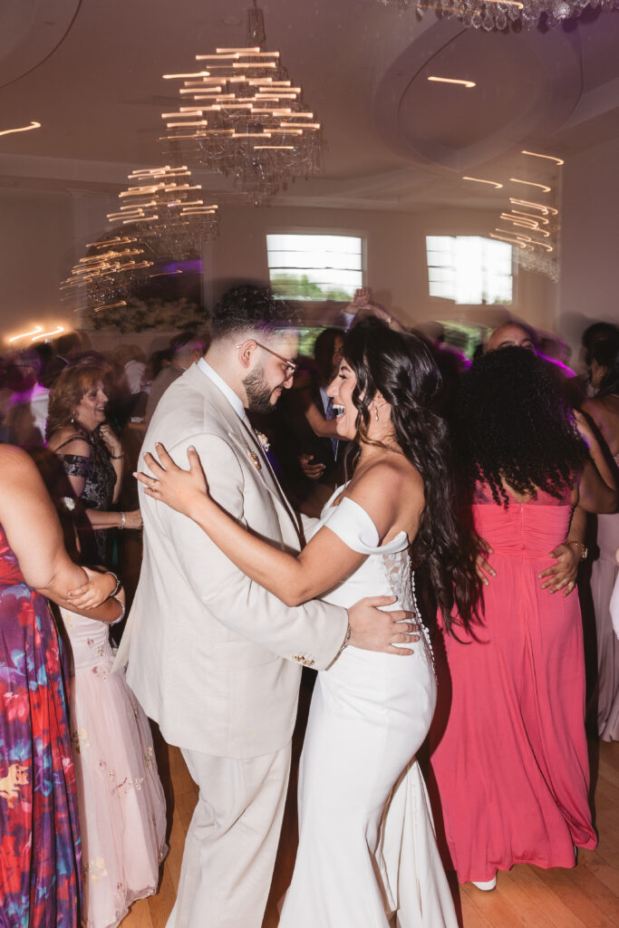 Blurred photo of bride and groom smiling and dancing together, joined with friends and family photographed by Philadelphia and New Jersey based travel wedding photographer, Madison Neumann Photography.
