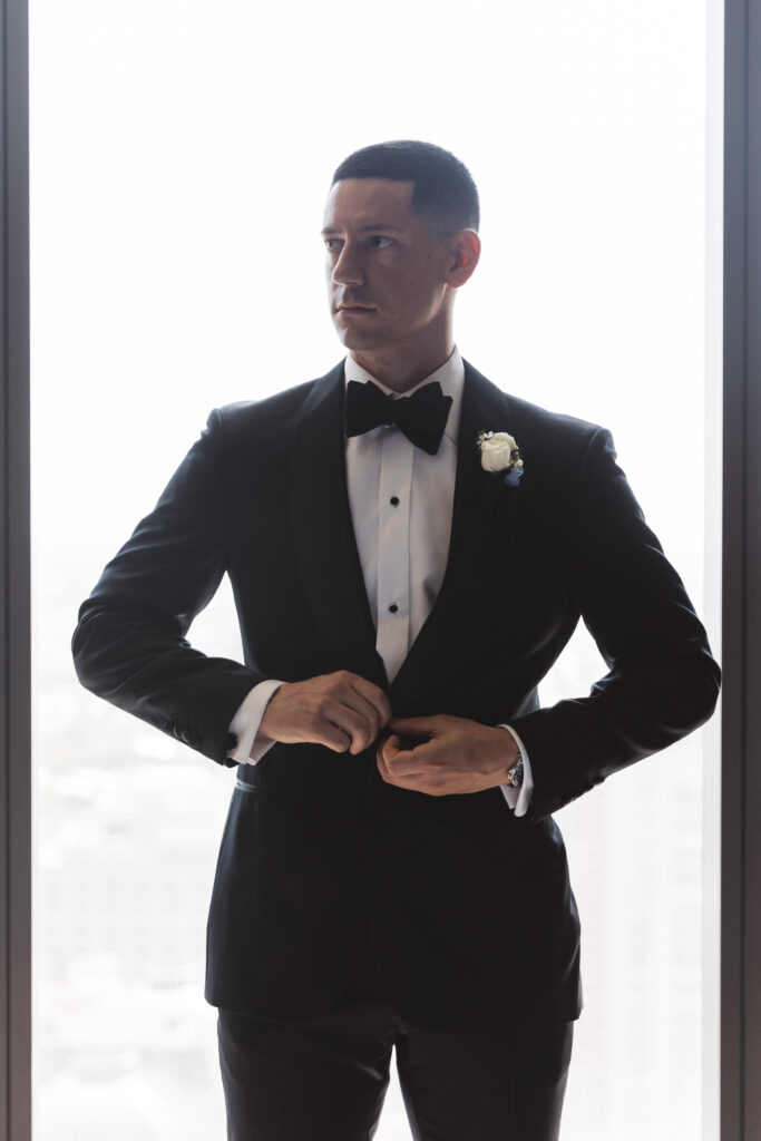 Portrait of groom buttoning his suit and looking off to the side, photographed by Philadelphia and New Jersey based travel wedding photographer, Madison Neumann Photography.