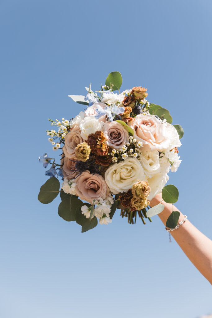 Artistic shot of the bouquet with the blue sky in the background, photographed by Philadelphia and New Jersey based travel wedding photographer, Madison Neumann Photography.