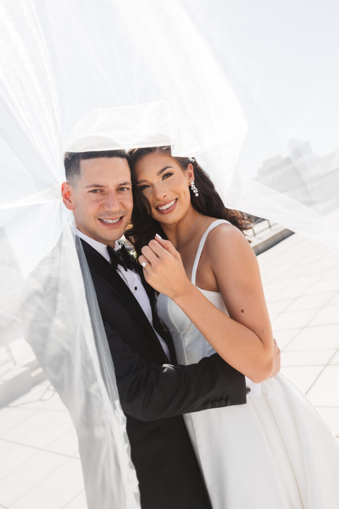 Bride and groom under the veil and smiling while embracing, photographed by Philadelphia and New Jersey based travel wedding photographer, Madison Neumann Photography.