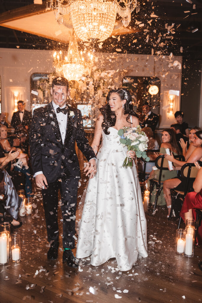 Wife and husband walk hand in hand down the aisle with confetti surrounding them as they exit, photographed by Philadelphia and New Jersey based travel wedding photographer, Madison Neumann Photography.
