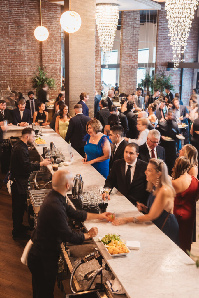 Shot of cocktail hour from the bar to see a bustling hub of loved ones gathered to celebrate, photographed by Philadelphia and New Jersey based travel wedding photographer, Madison Neumann Photography.