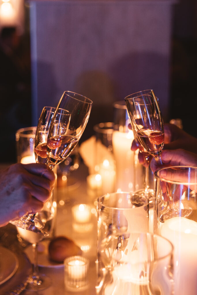 Beautiful shot of champagne glasses with a raspberry in them gathered for a toast, photographed by Philadelphia and New Jersey based travel wedding photographer, Madison Neumann Photography.