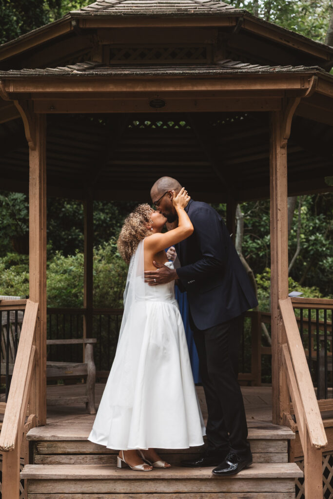 Bride and groom share their first kiss as husband and wife on the steps of the gazebo in Sayen Gardens in Hamilton, New Jersey. Photographed by Philadelphia and New Jersey based travel wedding photographer, Madison Neumann Photography.