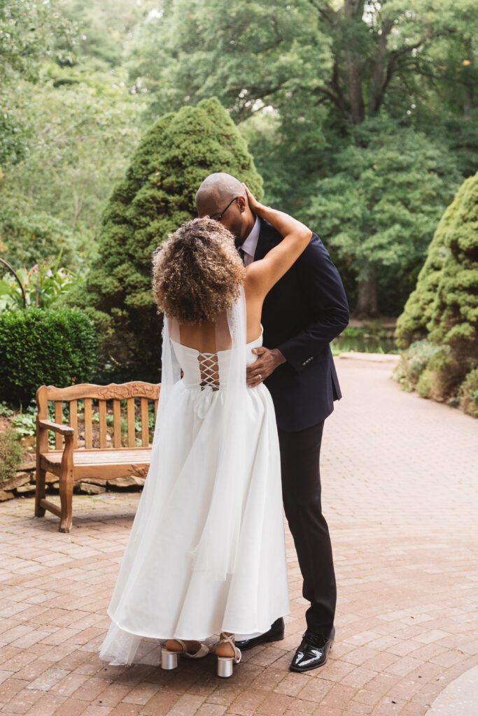 Shot taken from behind the bride, giving us a view of the beautiful lace-up back of her dress as she and her husband share a kiss, photographed by Philadelphia and New Jersey based travel wedding photographer, Madison Neumann Photography.