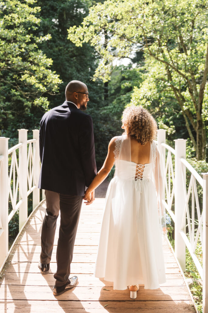 Newly weds walk over a bridge into sunlight, creating a beautiful glow covering them both, photographed by Philadelphia and New Jersey based travel wedding photographer, Madison Neumann Photography.