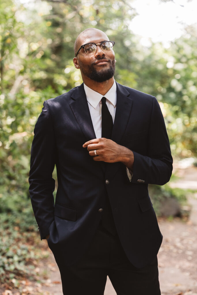 Portrait of groom in his suit with ring finger visible in the Sayen Gardens in Hamilton, NJ. Photographed by Philadelphia and New Jersey based travel wedding photographer, Madison Neumann Photography.