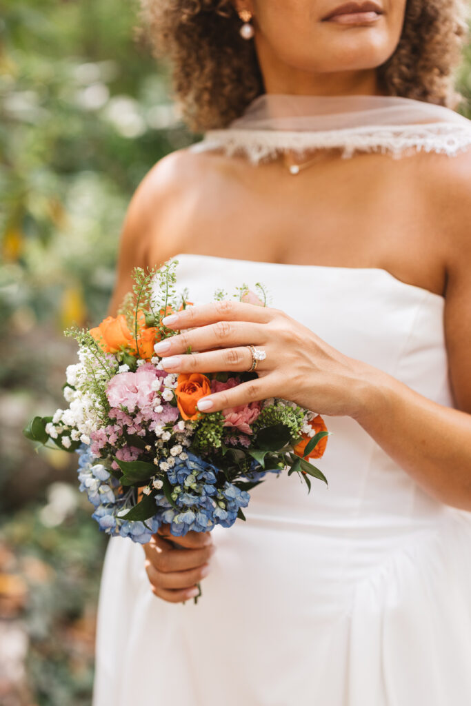 Detail shot of brides ring on her hand as she lightly touches her flowers, photographed by Philadelphia and New Jersey based travel wedding photographer, Madison Neumann Photography.