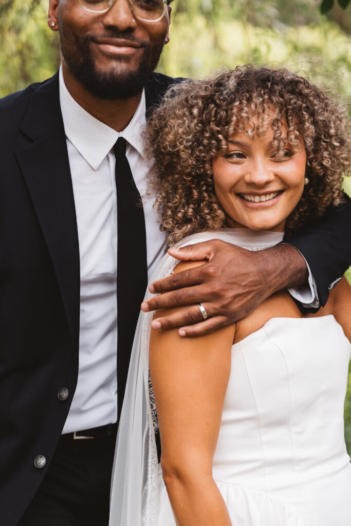 Groom holding his bride against his chest with one hand as they both smile, photographed by Philadelphia and New Jersey based travel wedding photographer, Madison Neumann Photography.